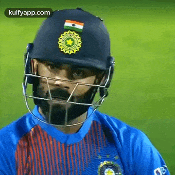 a close up of a cricket player wearing a helmet and a blue shirt .