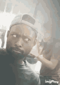 a man with a beard wearing a baseball cap is taking a selfie .