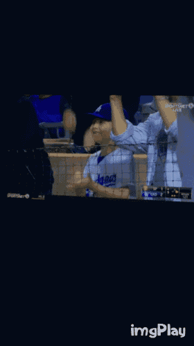 a boy wearing a dodgers jersey is waving his hands in the air