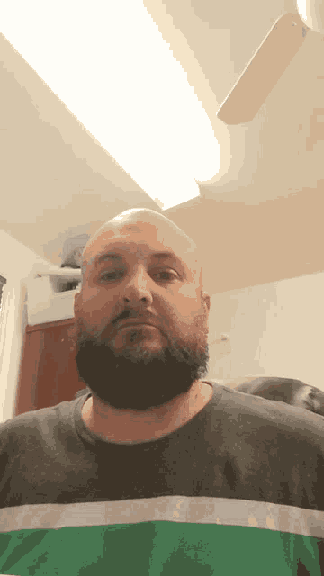 a man with a beard is wearing a striped shirt with the letter t on it