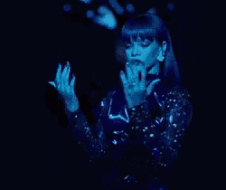 a woman with blue hair is dancing on a stage in a black dress .