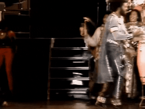a group of people are standing on a stage and dancing .