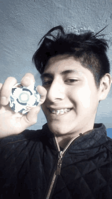 a young man with braces on his teeth is holding a toy