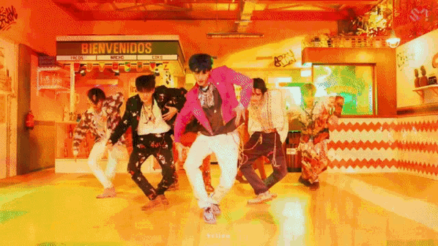 a group of people are dancing in front of a bienvenidos sign