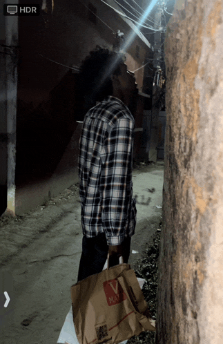 a man in a plaid shirt is holding a bag that says max on it