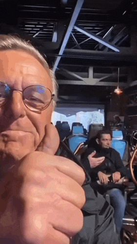 a man wearing glasses is giving the thumbs up sign