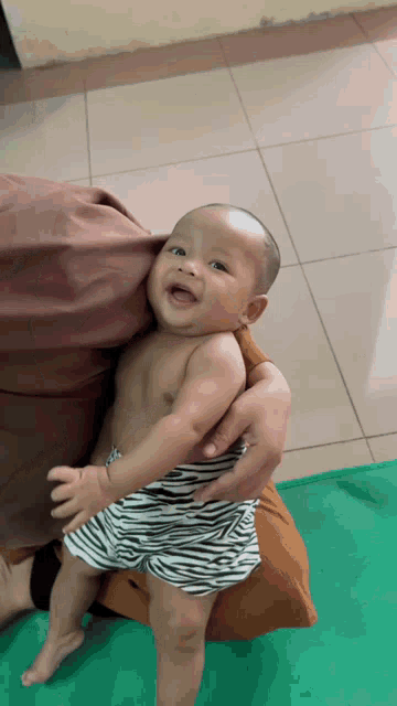 a baby wearing zebra shorts is being held by a woman