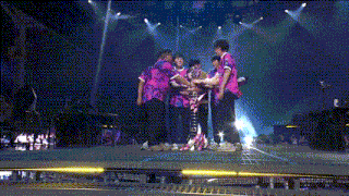 a group of people standing on a stage with one wearing a purple shirt that says ' nirvana ' on it