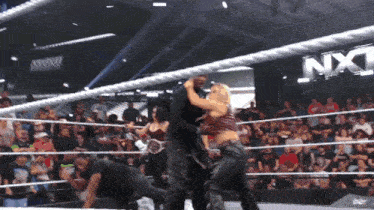 a wrestling match is underway in front of a nxt banner