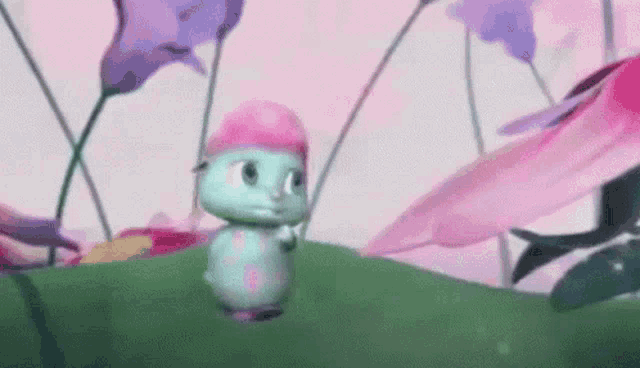a cartoon caterpillar wearing a pink hat is standing on a grassy hill surrounded by flowers .