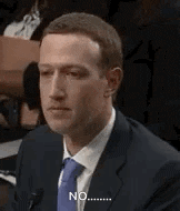 a man in a suit and tie is sitting in front of a microphone and making a funny face .