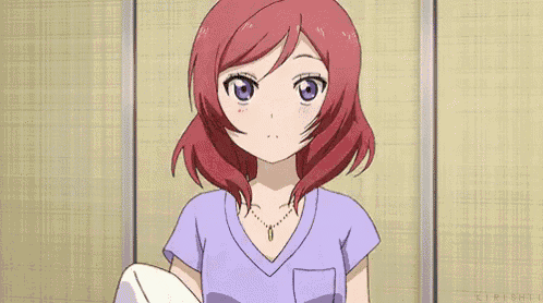 a girl with red hair and purple eyes is standing in front of a wall .