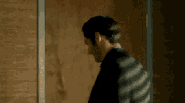 a man in a striped shirt stands in front of a door