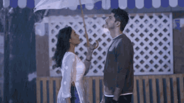a man and a woman are standing under an umbrella in the rain and kissing .