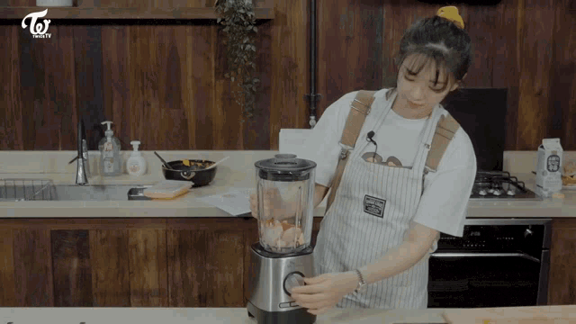 a woman in an apron is using a blender in a kitchen that says twice