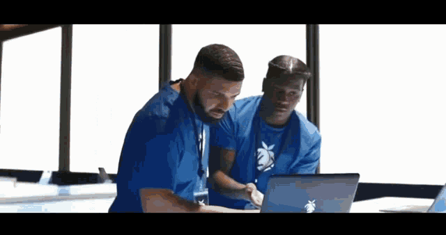 two men are looking at a laptop computer together .