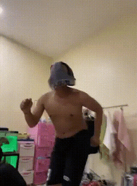 a man without a shirt is dancing in a room with a bunch of pink boxes
