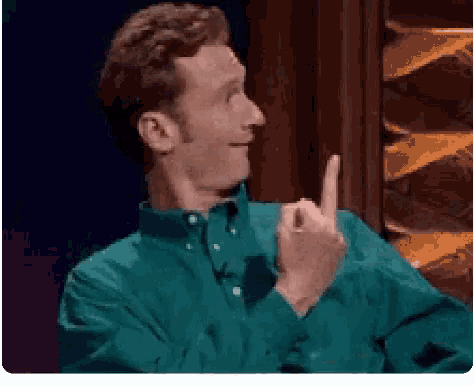 a man in a green shirt is making a funny face and giving the middle finger .