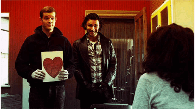 a man holding a card with a red heart on it