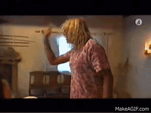 a man in a pink shirt is dancing in a room with a makeagif.com logo