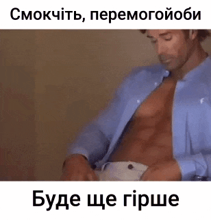 a shirtless man in a blue shirt is sitting on a bed and taking off his shirt .