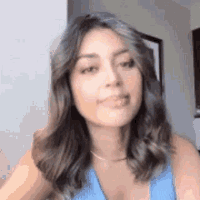 the woman is wearing a blue tank top and a necklace .