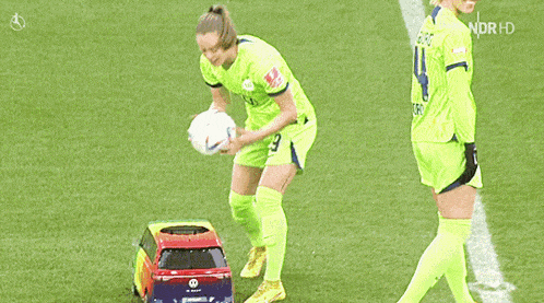 a soccer player wearing a number 4 jersey stands next to a toy car