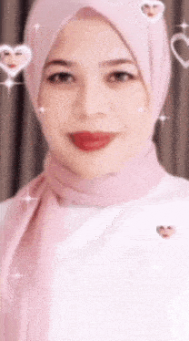 a woman wearing a pink hijab and white shirt is smiling .