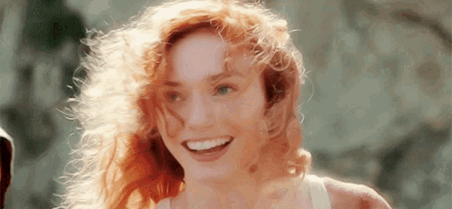 a woman with red hair and green eyes is smiling .