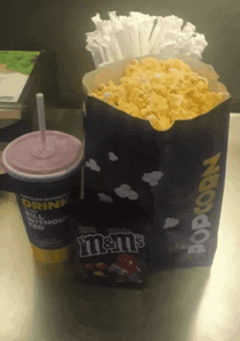 a bag of m & m 's sits next to a bag of popcorn on a table