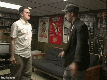 two men are standing in a room with posters on the wall including one that says ' espana '