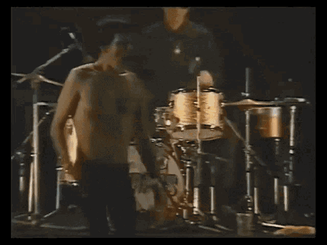 a man without a shirt is playing drums in front of a drum set that says cork