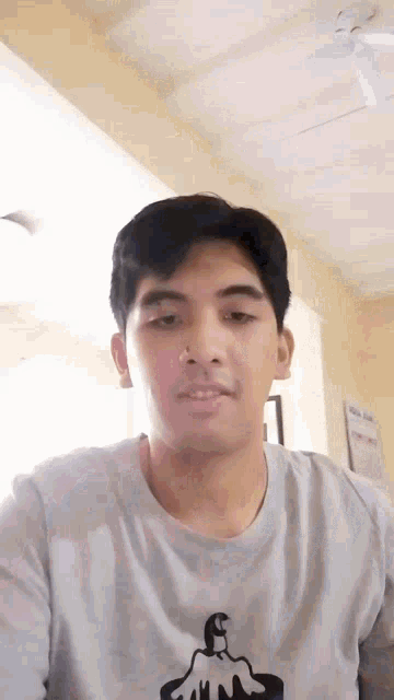 a young man wearing a gray shirt with a candle on it looks at the camera .