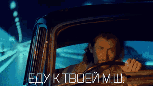 a man is driving a car with the words " edy k tvoei msh " written on the bottom