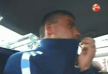 a man in a blue jacket is sitting in a car with a red hnv logo on the ceiling