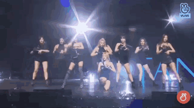 a group of women are dancing on a stage in front of a sign that says vlive on it .