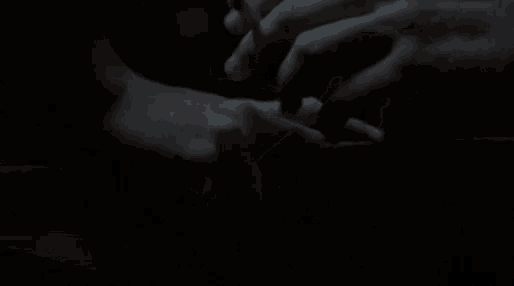 a man is smoking a cigarette in the dark while holding another man 's hand .