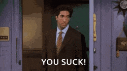a man in a suit and tie is standing in front of a door and says `` you suck '' .