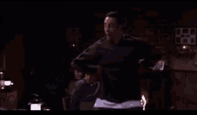 a man is dancing in a dark room with a brick wall