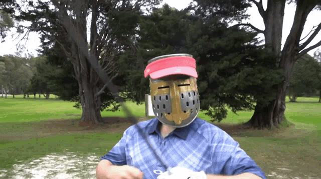 a man wearing a helmet and visor is holding a golf club on a golf course