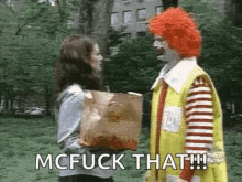 a mcdonald 's clown is talking to a woman holding a bag of food .