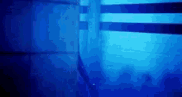 a person is swimming in a pool with a blue light shining on them .