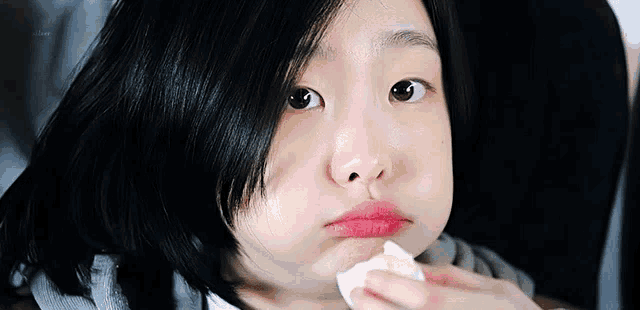 a close up of a young girl holding a napkin to her mouth .