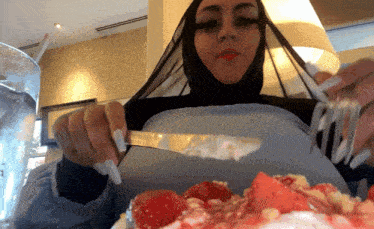 a woman in a hijab holds a fork over a plate of food