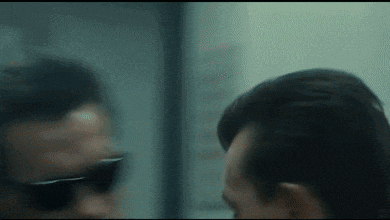 a blurry picture of a man wearing sunglasses looking at another man .