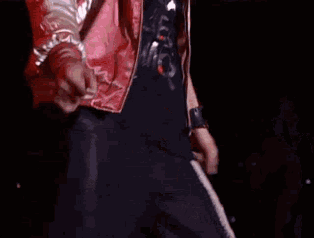 a man in a red jacket and black shirt is standing on a stage .