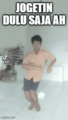 a man is dancing in a room with a caption that says jogetin dulu saja ah .