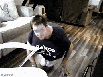 a man is doing push ups in a living room while wearing a shirt that says maxco on it .