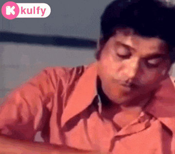 a man in a pink shirt is sitting down with his eyes closed