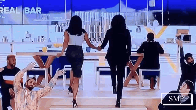 a group of people are dancing in front of a sign that says " real bar "